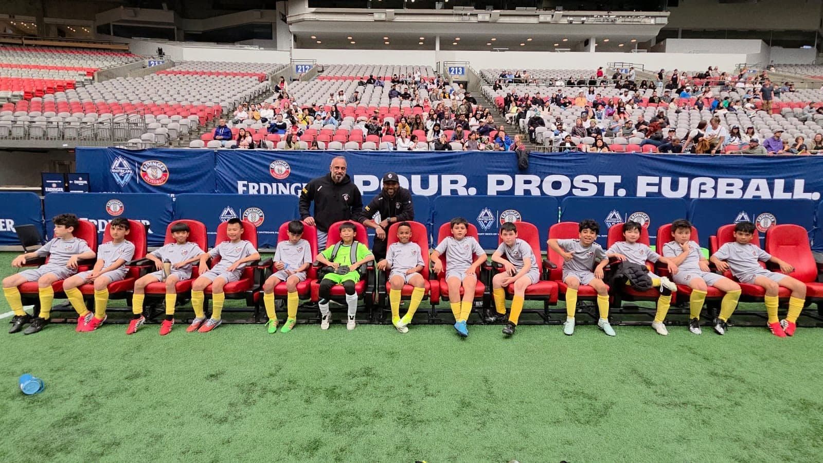 ACBC players and their coaches on the team bench inside BC Place